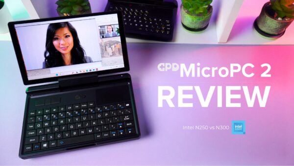 GPD MicroPC 2 समीक्षा वीडियो का एक गतिशील थंबनेल। अग्रभूमि में एक काला GPD MicroPC 2 प्रमुखता से दिखाई दे रहा है, जो खुला हुआ है और दर्शक की ओर झुका हुआ है, और इसकी स्क्रीन पर एक महिला के चेहरे वाली वीडियो कॉन्फ्रेंस कॉल दिखाई दे रही है। लैपटॉप का कॉम्पैक्ट कीबोर्ड और ट्रैकपैड दिखाई दे रहे हैं। पृष्ठभूमि में गमलों में लगे पौधों वाला एक सफेद शेल्फ और एक और GPD MicroPC 2 है। लैपटॉप के नीचे डेस्क का रंग चटक गुलाबी और बैंगनी रंग का है। लैपटॉप के दाईं ओर बड़े सफेद अक्षरों में "GPD MicroPC 2 समीक्षा" लिखा है, और नीचे छोटे अक्षरों में "Intel N250 बनाम N300" और "Intel इनसाइड" लोगो लिखा है।     