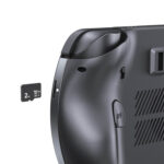 일반 흰색 배경에 짙은 회색 GPD WIN 5 휴대용 게임 콘솔의 뒷면을 클로즈업하여 각도로 촬영한 사진입니다. 이 이미지는 2TB microSD 카드가 부분적으로 삽입되어 있는 microSD 카드 슬롯에 초점을 맞추고 있습니다. 질감이 있는 뒷면 그립과 "R4" 숄더 버튼도 볼 수 있습니다.